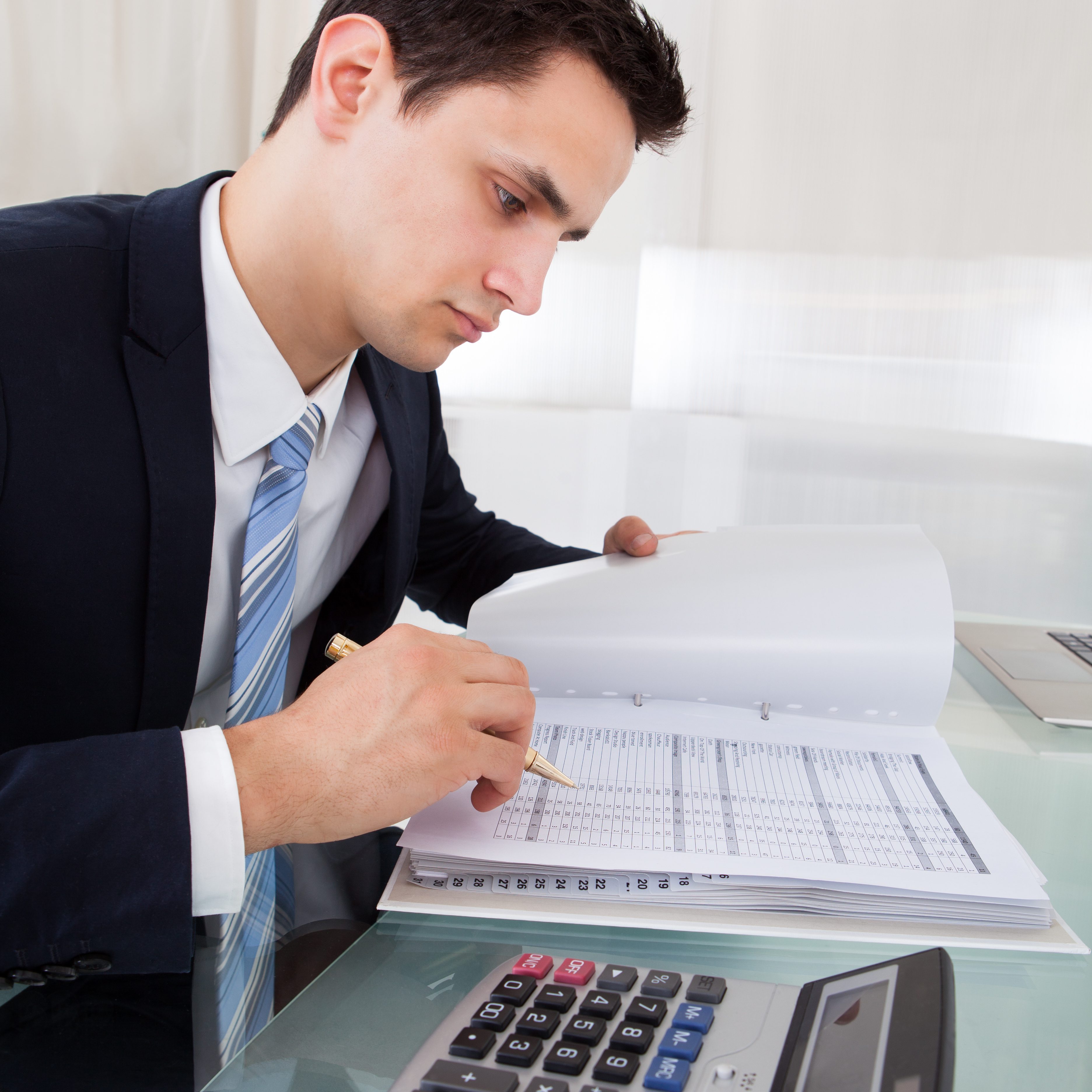 Cropped image of businessman calculating expense at desk in office